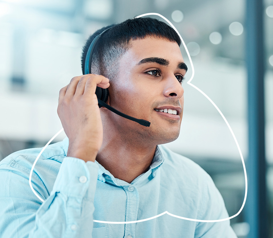 Hombre con auriculares en un entorno de oficina, sonriendo mientras habla por teléfono. Predominan tonos claros y neutros.