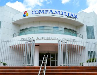 Edificio de Comfamiliar Atlántico con acceso principal, cercado y entorno ajardinado, bajo un cielo parcialmente nublado.